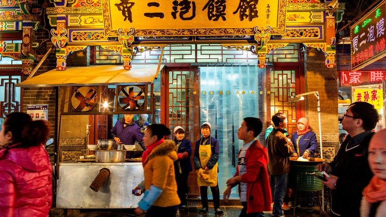清真美食街上的一个餐馆的工作人员站在餐馆外。Workers stand outside a restaurant in the Muslim Street area..jpg